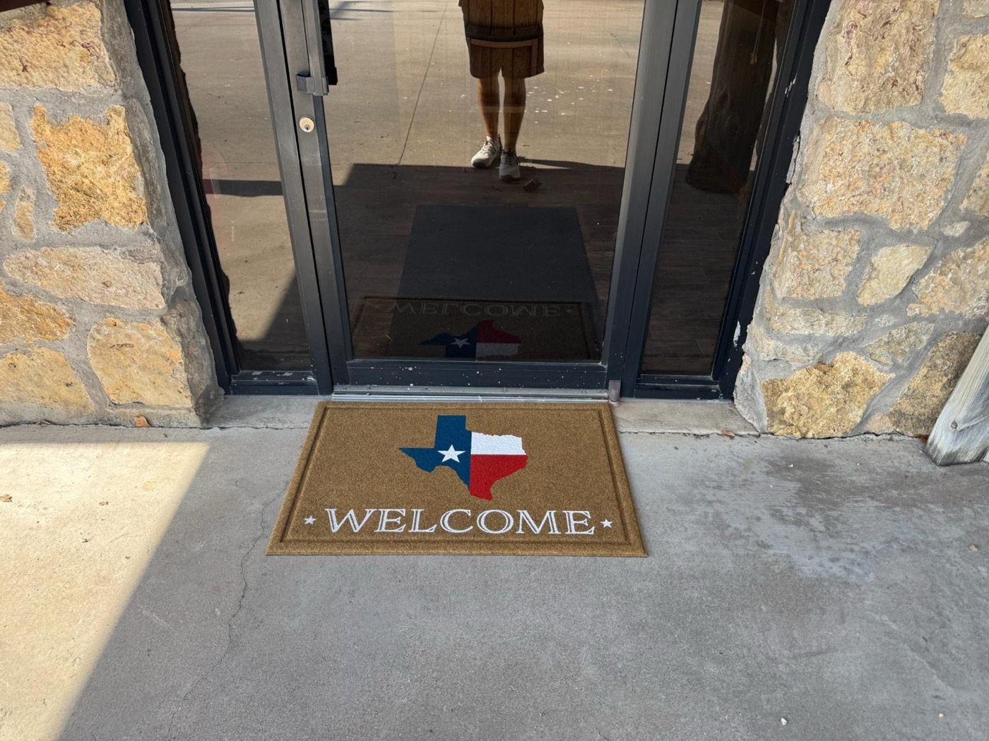 Texas-flag welcome mat at the stone entrance of the park office